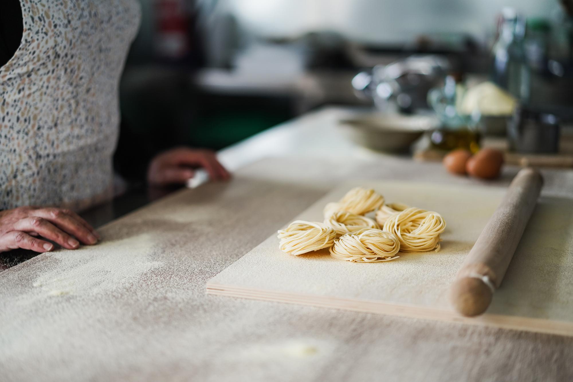 Mano che prepara pasta fresca sul piano